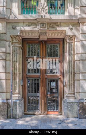 Barcelone – Espagne – 23 mai 2026 : Entrée de bâtiment classique, porte en bois avec grilles en fer forgé, piliers en pierre décoratifs, style vintage européen Banque D'Images