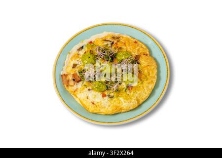Omelette saine avec sauce à l'avocat, micro-pousses et légumes sur une assiette bleue Banque D'Images