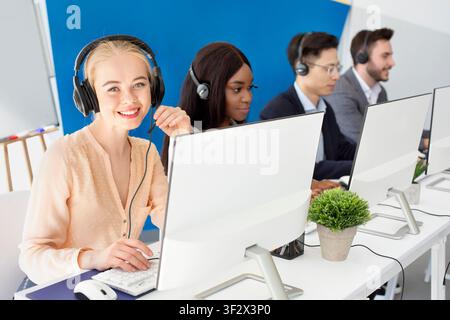 Une équipe multinationale d'opérateurs de centre d'appels s'adressant aux clients en ligne au bureau moderne Banque D'Images