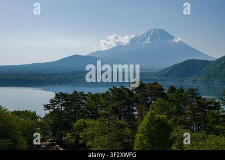 Cette vue met en scène le mont Fuji tel qu'il est vu depuis les rives sereines du lac Motosu dans la préfecture de Yamanashi, au Japon. Le paysage boisé entourant le l Banque D'Images