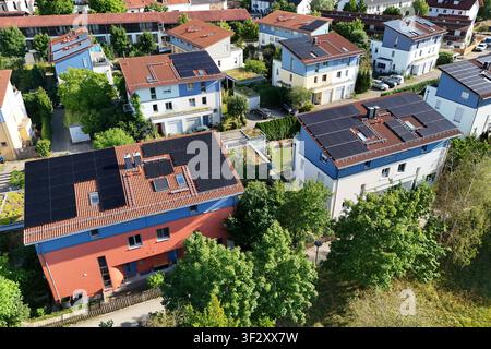 La photographie aérienne montre plusieurs maisons individuelles et maisons mitoyennes dans un quartier résidentiel moderne avec des systèmes photovoltaïques à grande échelle sur les toits. Les modules solaires utilisent une grande partie des surfaces des toits pour la production d'électricité durable Banque D'Images
