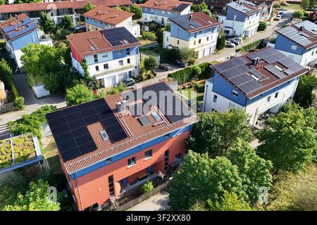 La photographie aérienne montre plusieurs maisons individuelles et maisons jumelées dans un quartier résidentiel moderne avec des systèmes photovoltaïques à grande échelle sur les toits. Les modules solaires utilisent une grande partie des surfaces des toits pour une production d'énergie durable. Banque D'Images