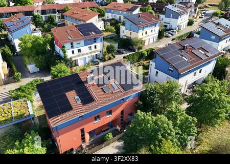La photographie aérienne montre plusieurs maisons unifamiliales et maisons jumelées dans un quartier résidentiel moderne avec des systèmes photovoltaïques à grande échelle sur les toits. Les modules solaires utilisent la plupart des surfaces des toits pour une production d'énergie durable. Ver Banque D'Images