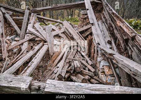 Ancienne maison abandonnée s'effondrant en un tas de débris de bois pourrissants et de murs de pierre, montrant la destruction et la négligence Banque D'Images