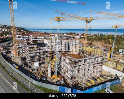 Vue aérienne d'un chantier de construction avec plusieurs grues jaunes, des immeubles d'appartements inachevés et des échafaudages près de la mer Adriatique à Izola Banque D'Images