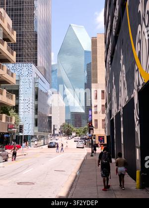 DALLAS, TX, USA - 11 JUILLET 2026 : Des piétons déambulent le long d'une rue animée bordée par des gratte-ciel modernes dans le centre-ville de Dallas. La façade en verre frappante o Banque D'Images