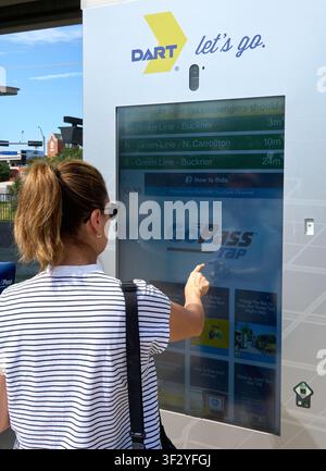DALLAS, TX, USA - 11 JUILLET 2026 : Une femme interagit avec un écran tactile DART dans une station à Dallas, Texas, vérifiant les horaires des tramways. DART Banque D'Images