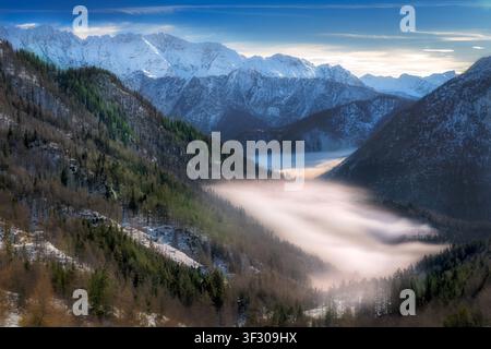 Baignés dans la lumière dorée d’un soleil de mi-après-midi, les pics déchiquetés des Alpes juliennes s’élèvent triomphalement au-dessus d’une mer de brume. Vue depuis le col de Vršič i Banque D'Images