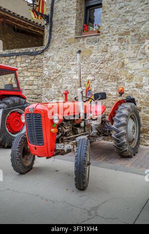 Castellgali - Espagne - 2 mai 2026 : Tracteur rouge vintage garé devant un mur de pierre traditionnel, machines agricoles antiques, véhicule agricole Banque D'Images
