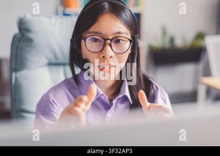 Représentante du service client asiatique concentrée avec casque travaillant au bureau Banque D'Images
