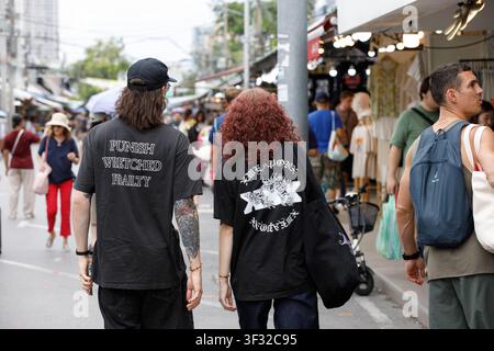 BANGKOK, THAÏLANDE - 12 JUILLET 2026 : Couple de touristes explorant un marché en plein air à Bangkok, vu de dos. Banque D'Images