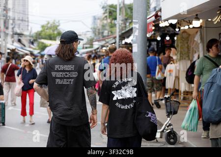 BANGKOK, THAÏLANDE - 12 JUILLET 2026 : Couple de touristes explorant un marché en plein air à Bangkok, vue de dos. Banque D'Images