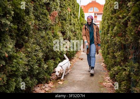 Heureuse jeune femme promenant chien dans la rue appréciant l'automne Banque D'Images