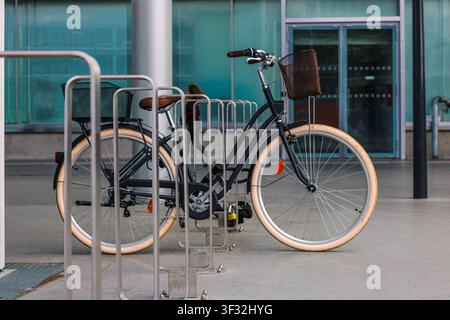 Vélo garé dans une aire de stationnement moderne pour vélos à l'extérieur d'un bâtiment public Banque D'Images