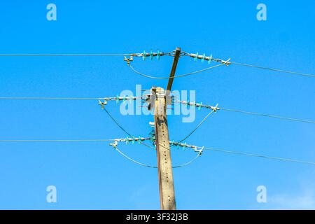 Poteau utilitaire en béton avec fils électriques contre un ciel bleu Banque D'Images