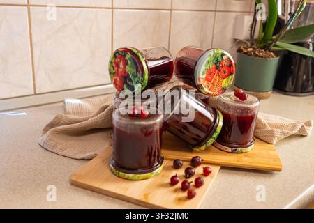Abondance de confiture de groseilles rouges maison dans plusieurs bocaux en verre, préparation de stockage hivernal, confiture de baies biologiques et arrangement de fruits frais Banque D'Images