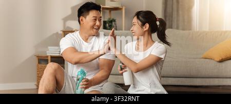 Couple asiatique heureux s'adonnant au nettoyage de la maison ensemble à la maison, atmosphère positive Banque D'Images
