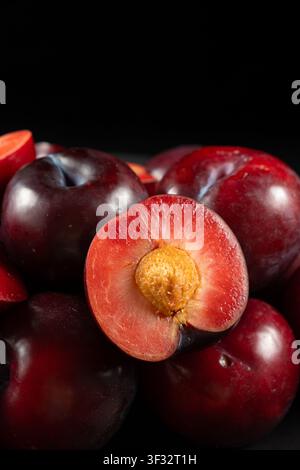 tas de prunes rouges foncées fraîches sur fond noir Banque D'Images