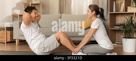 Couple faisant de l'exercice ensemble à la maison, homme et femme asiatiques engagés dans une activité physique, concept de perte de poids Banque D'Images