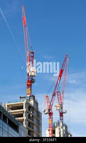 Deux grues à flèche pivotante sur des cœurs d'ascenseur en béton sur un chantier de construction de grande hauteur à la City de Londres, Angleterre, Royaume-Uni Banque D'Images