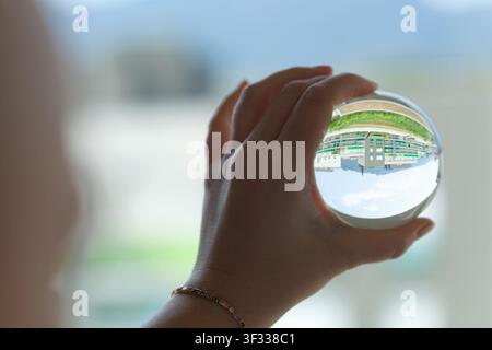 Main tenant une boule de cristal avec un paysage inversé Banque D'Images