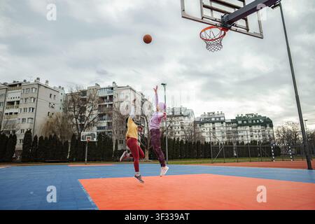 Deux jeunes femmes sautant en jouant au basket-ball en plein air Banque D'Images
