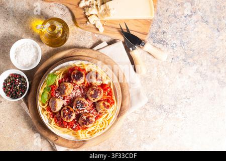Une assiette de spaghettis classiques garnie de boulettes de viande dorées et d'une riche sauce tomate sur un plat en céramique légère. Banque D'Images