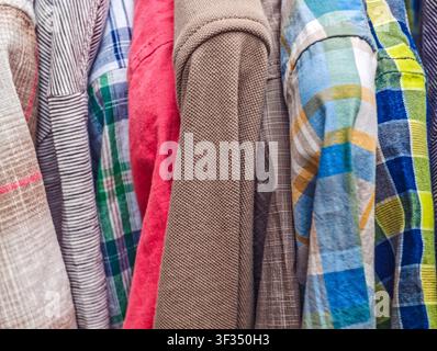 Collection de vêtements avec différents tissus, couleurs et textures, suspendus soigneusement dans un placard, illustrant la mode et le style Banque D'Images