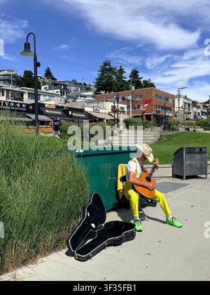 Un musicien joue de la guitare acoustique sur la promenade du front de mer à White Rock, Colombie-Britannique, Canada. Banque D'Images