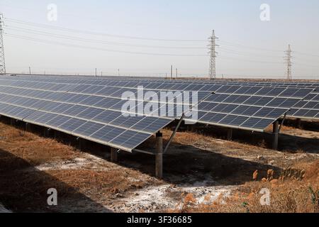 Grand plan d'une centrale solaire photovoltaïque à grande échelle présentant des rangées de panneaux solaires bleus installés sur des supports métalliques, dans un paysage sec et doré Banque D'Images
