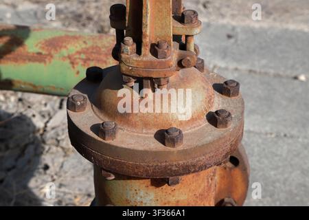 Photographie en gros détaillée d'une vanne métallique industrielle fortement rouillée et d'un assemblage de bride, comportant plusieurs boulons couverts de corrosion et un temps Banque D'Images