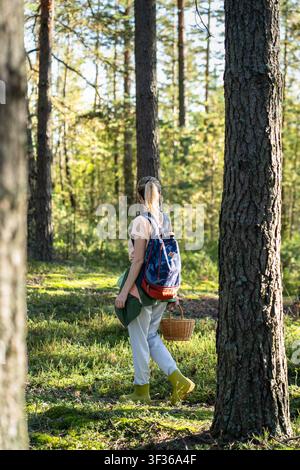 Femme chercheuse cueillant dans la nature, marchant dans une forêt d'automne avec un panier pour récolter des champignons Banque D'Images