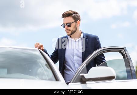 Un jeune entrepreneur sérieux se présente dans sa voiture au cœur de la ville Banque D'Images