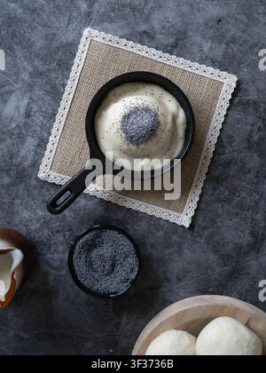 Image alimentaire en vue plongeante de dumplings traditionnels servis dans une poêle avec une sauce à la vanille et une garniture de graines de pavot Banque D'Images