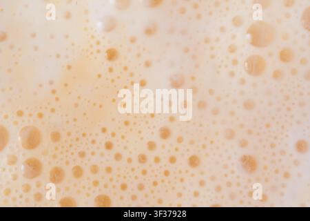 gros plan de la texture d'un milkshake au mangue. Fond de mousse de milkshake à l'orange, photo macro de bulles de smoothie aux fruits, vue de dessus d'un cocktail mousseux et lacté fouetté Banque D'Images