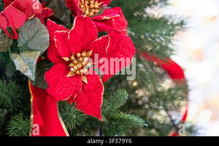 Ornement floral rouge de Noël accroché à un arbre. Vue rapprochée. Banque D'Images