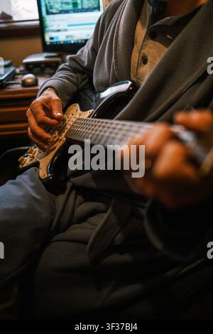Musicien jouant de la guitare électrique en portant une robe de chambre dans un studio de musique à domicile Banque D'Images