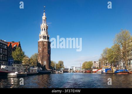Amsterdam, pays-Bas - 18 avril 2026 : tour Montelbaanstoren et ponts historiques le long du canal Oudeschans dans le centre d'Amsterdam par un jour de printemps ensoleillé Banque D'Images