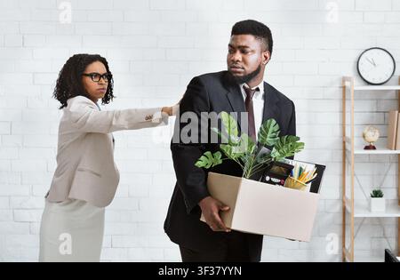 Perte d'emploi et chômage. Le patron féminin a tiré un employé américain africain au bureau Banque D'Images