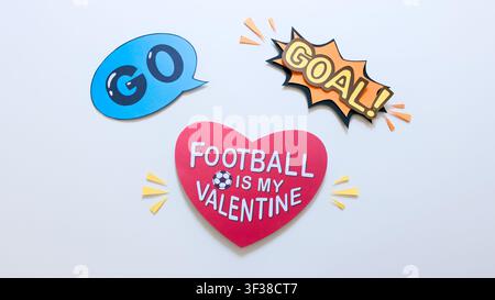 Un flat lay vibrant mettant en avant des découpes de papier qui expriment un amour fort pour le football, comprenant un panneau en forme de cœur, une bulle de dialogue ‚GO‘ et un ‚BUT !‘ Banque D'Images