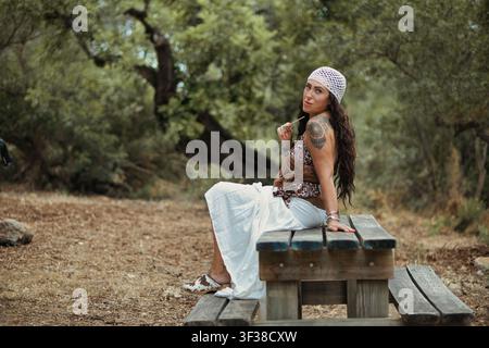 Femme chic bohème stylée assise dans le parc, profitant d'un moment de paix seule Banque D'Images