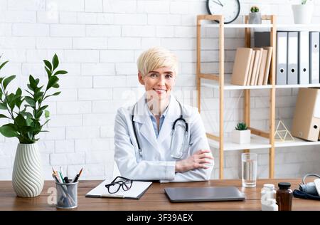 Visite d'un thérapeute au bureau. Femme souriante médecin assis à table Banque D'Images