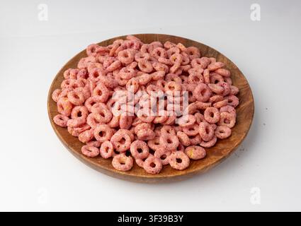 Anneaux de céréales roses isolés, boucles de riz pour petit-déjeuner fruité, collation de céréales de maïs sur fond blanc Banque D'Images