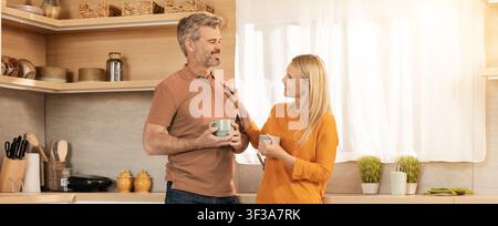Couple mature caucasien heureux profitant d'un café ensemble dans la cuisine, concept de style de vie à la maison Banque D'Images