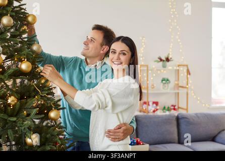 Portrait d'un couple heureux décorant un arbre pendant le Nouvel An ou Noël à la maison Banque D'Images