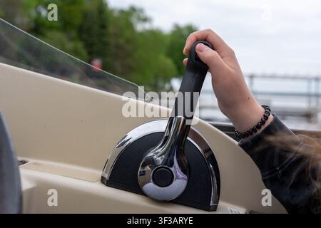 Un gros plan de la main d'une personne actionnant l'accélérateur et le levier de vitesse sur une console de bateau à ponton moderne. Banque D'Images