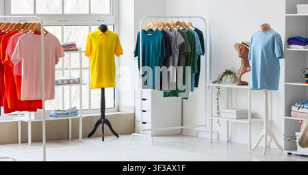Des t-shirts colorés exposés sur des mannequins et des rayons dans un magasin de vêtements lumineux Banque D'Images