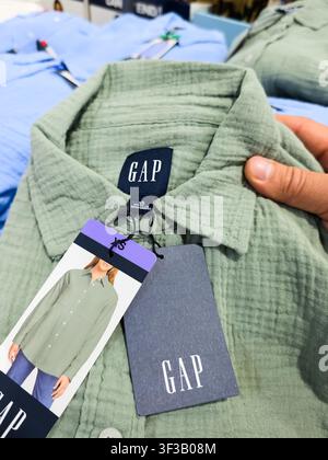 PLANO, TX, USA - 19 JUIN 2026 : Un t-shirt Gap vert est mis en avant avec ses étiquettes dans un magasin Costco à Plano, Texas. Gap est connu pour ses vêtements décontractés an Banque D'Images