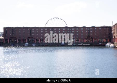 La grande roue de Liverpool s'élève derrière les entrepôts historiques en briques rouges du Royal Albert Dock à Liverpool, Merseyside, Angleterre, Royaume-Uni. Banque D'Images