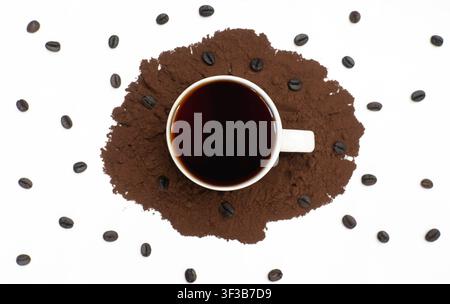 Tasse de café noire sur du café moulu avec des grains éparpillés Banque D'Images